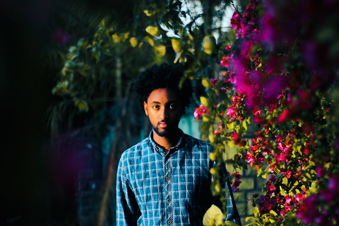 man standing surrounded by pink flowers