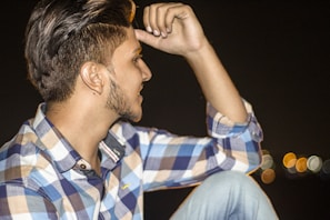 Artistic shot of a man styling his hair using roqvel gel, with cityscape blurred behind