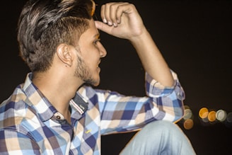 Artistic shot of a man styling his hair using roqvel gel, with cityscape blurred behind