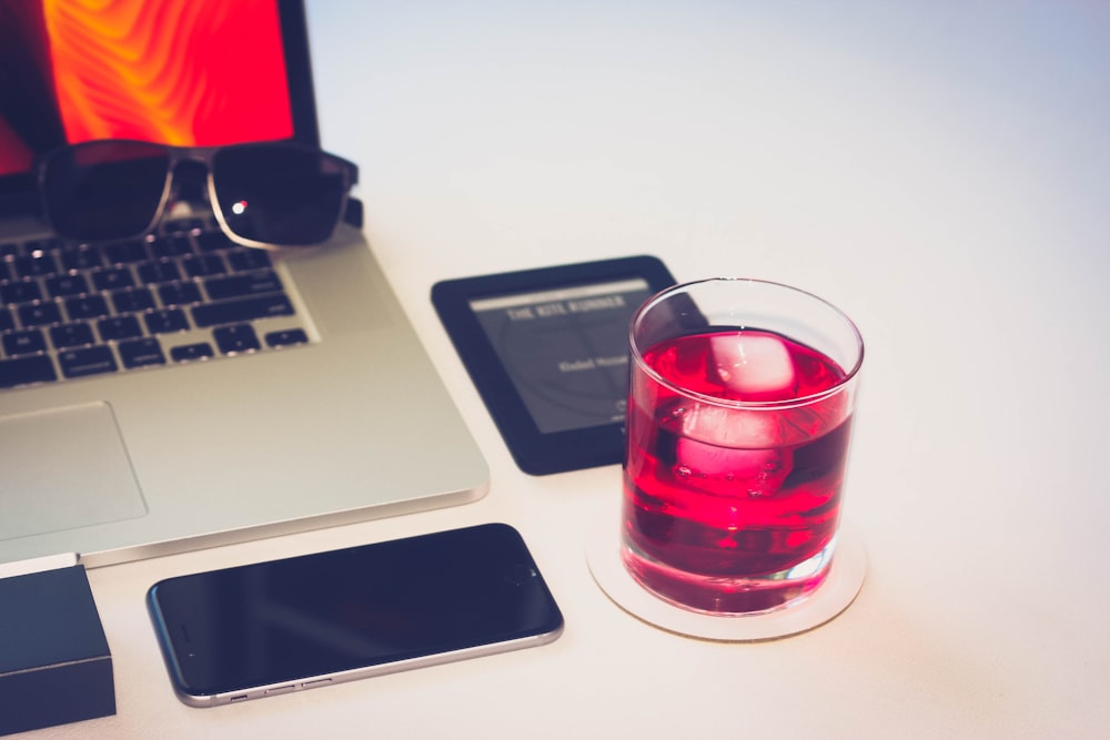 vaso de vidrio transparente al lado de la MacBook Pro