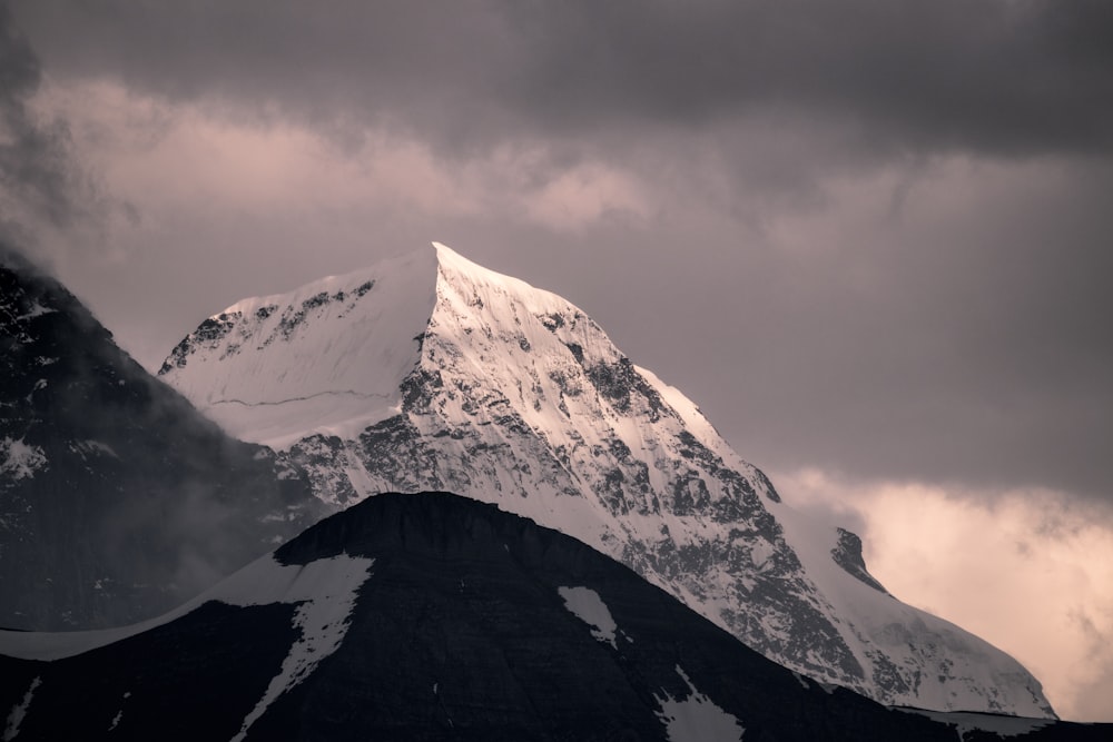 mountain covered by snow under white clouds at daytime
