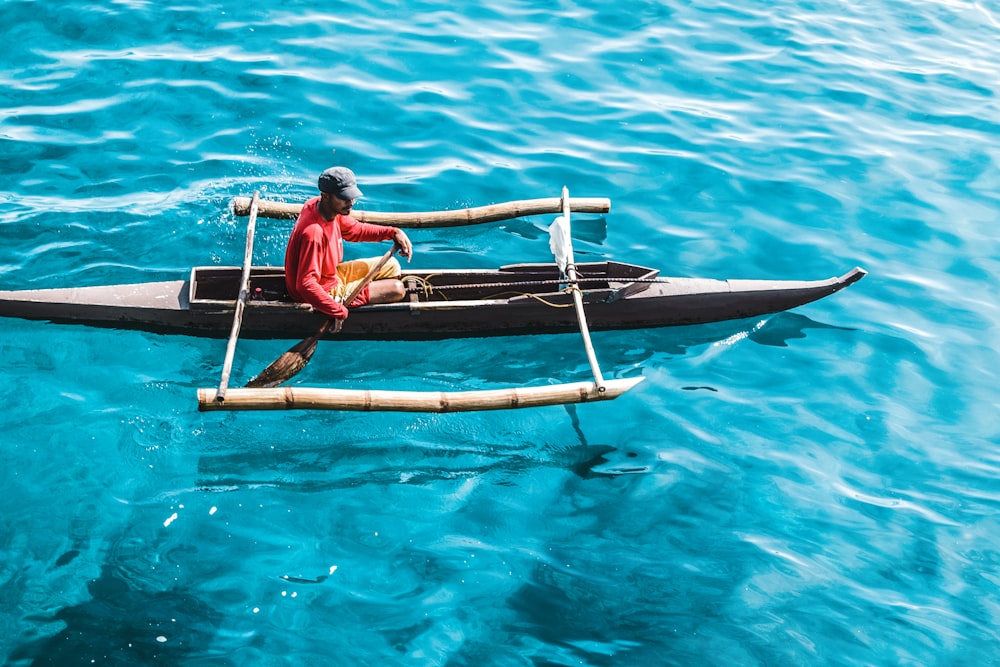 man riding row boat on sea