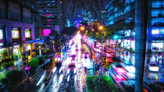 A bustling city street at night with colorful neon signs reflecting on wet pavement.