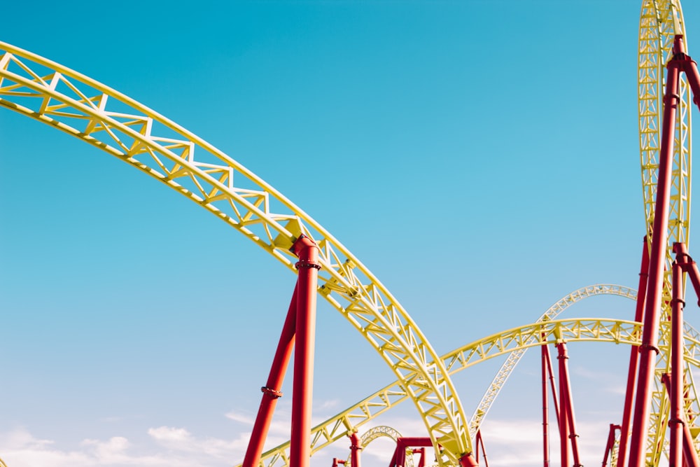 yellow and red roller coaster under blue sky at daytime