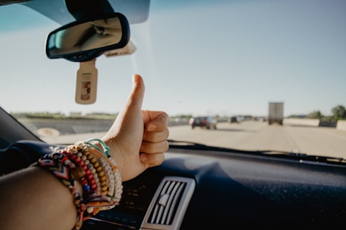 A professional truck driver in uniform giving a thumbs up inside the cabin.