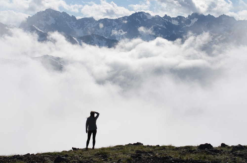 Persona de pie en la cima de la montaña con el mar de nubes durante el día