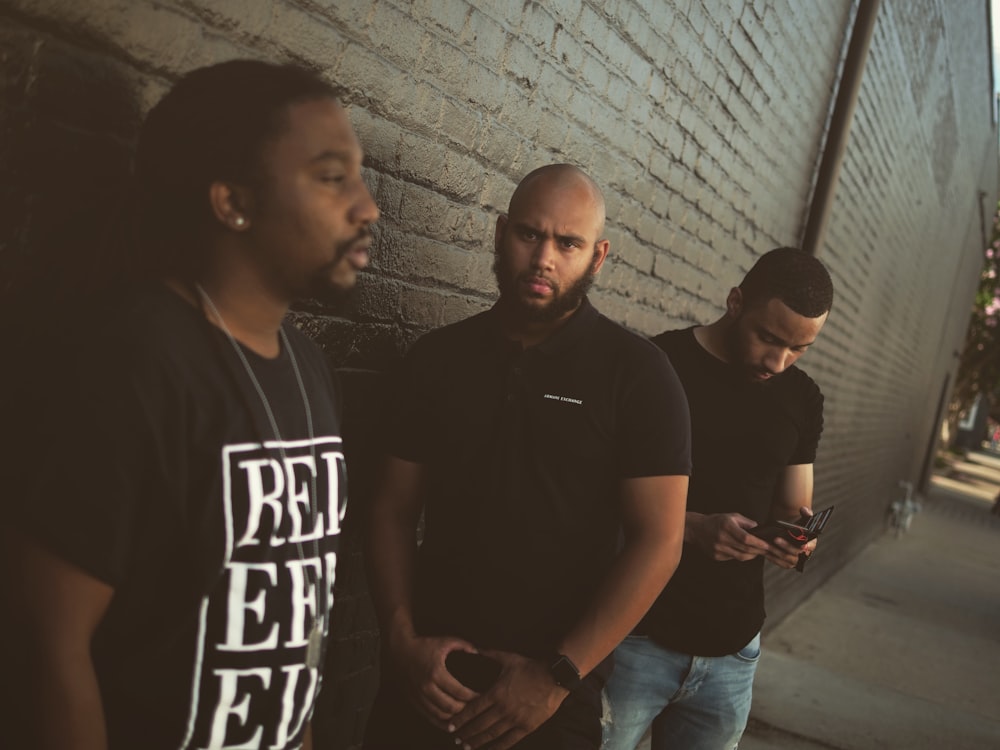 three men standing near wall