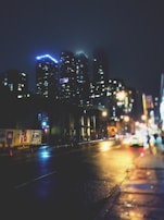 Nighttime cityscape of Bogotá illuminated with warm yellow and green lights reflecting off wet streets.