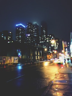 Nighttime cityscape of Bogotá illuminated with warm yellow and green lights reflecting off wet streets.