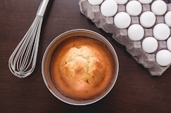 baked muffins beside tray of eggs and whisker