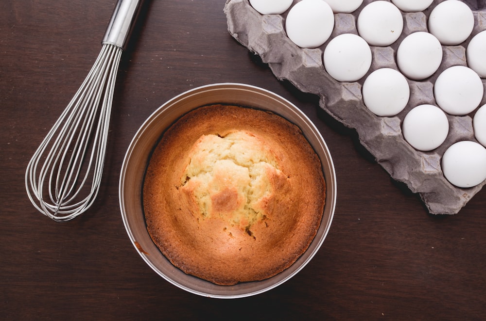 baked muffins beside tray of eggs and whisker