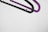 Two plastic hangers, one black and one purple, are suspended against a plain white background. They are overlapping slightly, with a minimalist and modern aesthetic.