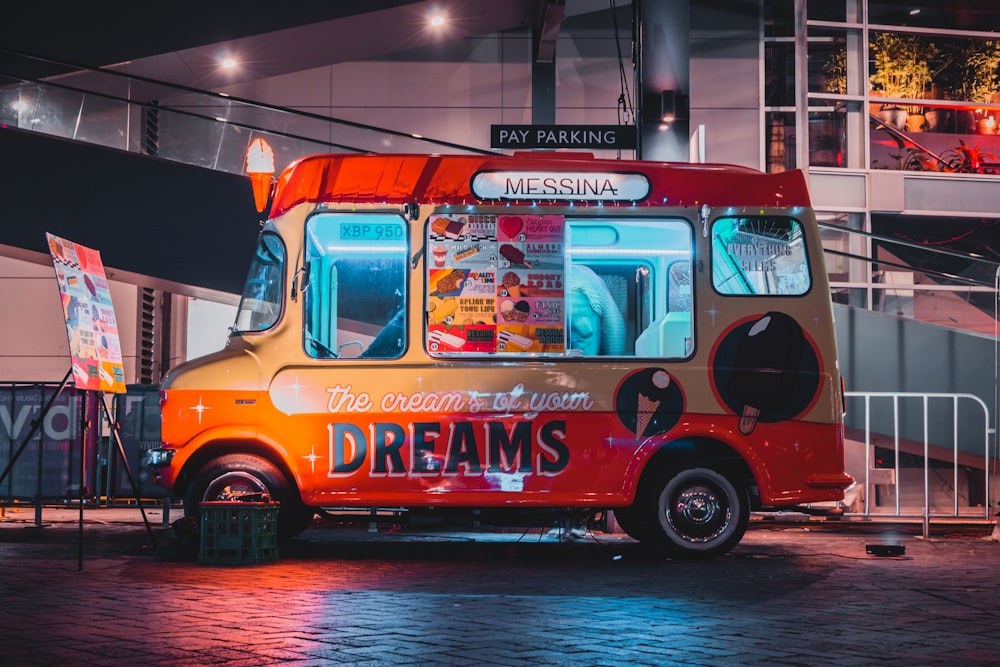 furgoneta de comida Dreams roja y gris estacionada frente al edificio