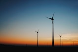 Wind turbine silhouette at sunset symbolizing growth and energy.