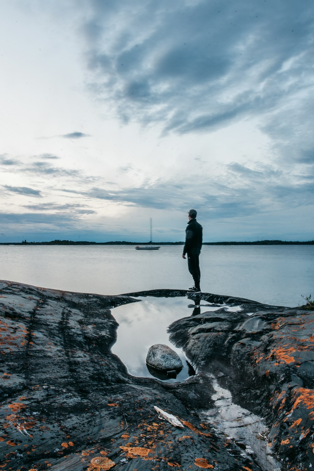 a man standing on top of a rock next to a body of water