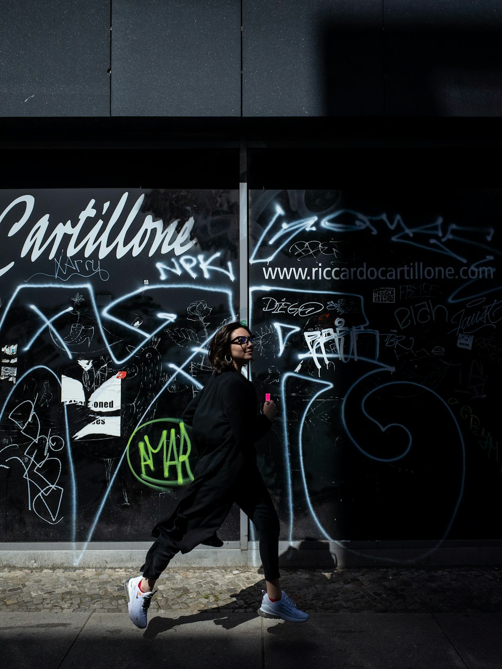 mujer caminando al lado de la obra de arte del graffiti