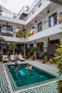 two men on pool beside three beige loungers