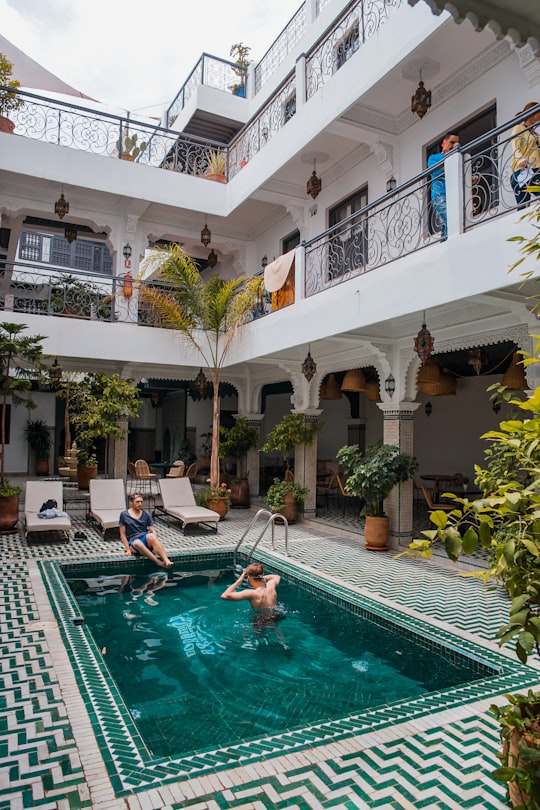 two men on pool beside three beige loungers in Marrakech Morocco