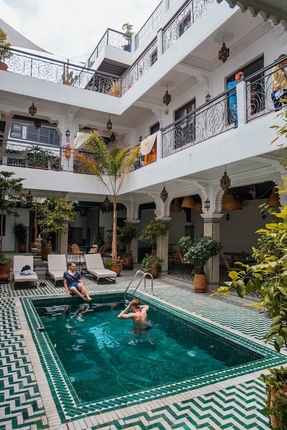 Dos hombres en la piscina junto a tres tumbonas beige