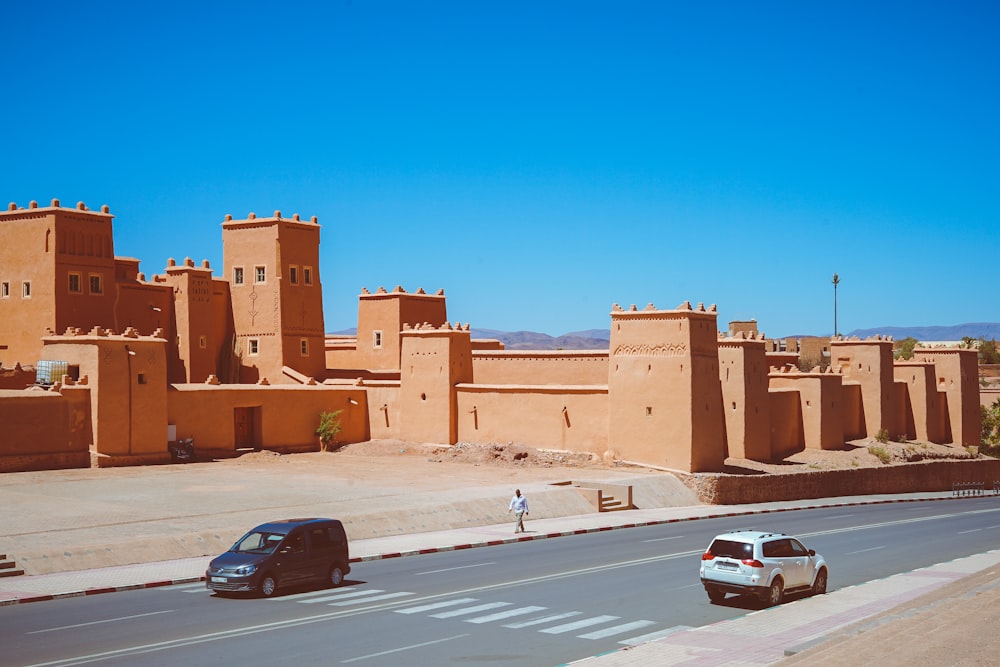 two cars passing near brown temple