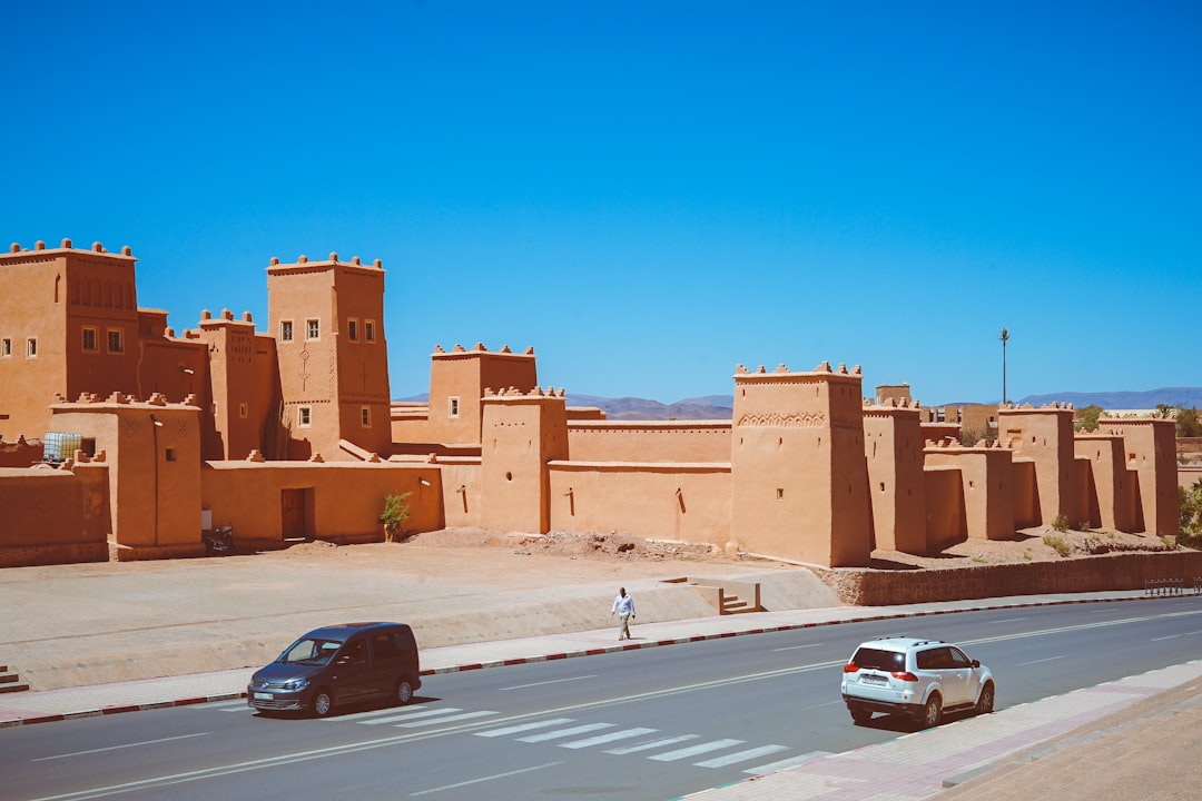 two cars passing near brown temple, Moroccan city