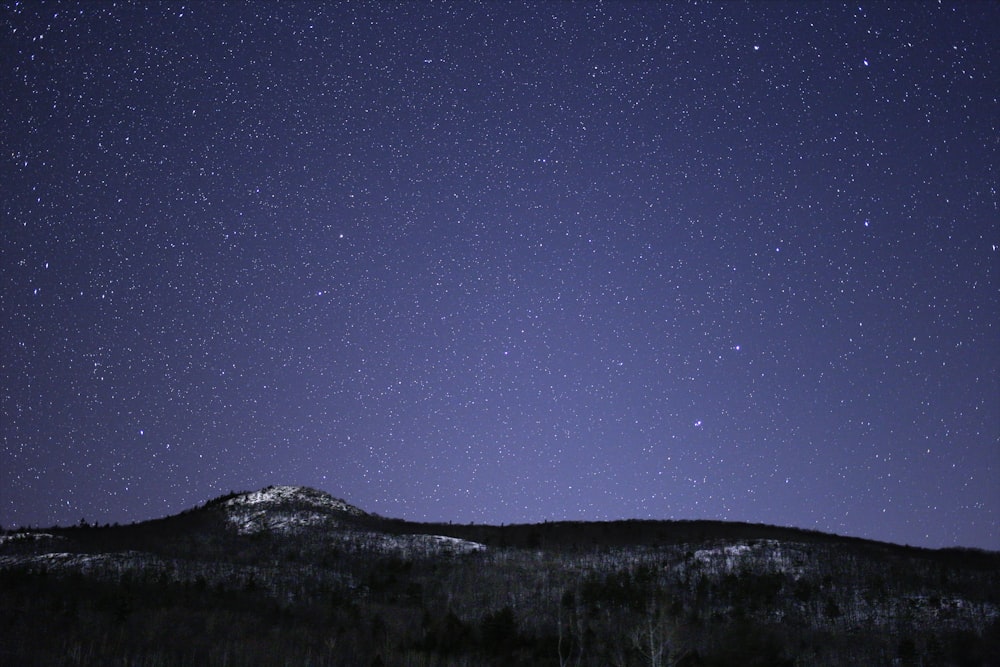 silhouette of mountain against stars