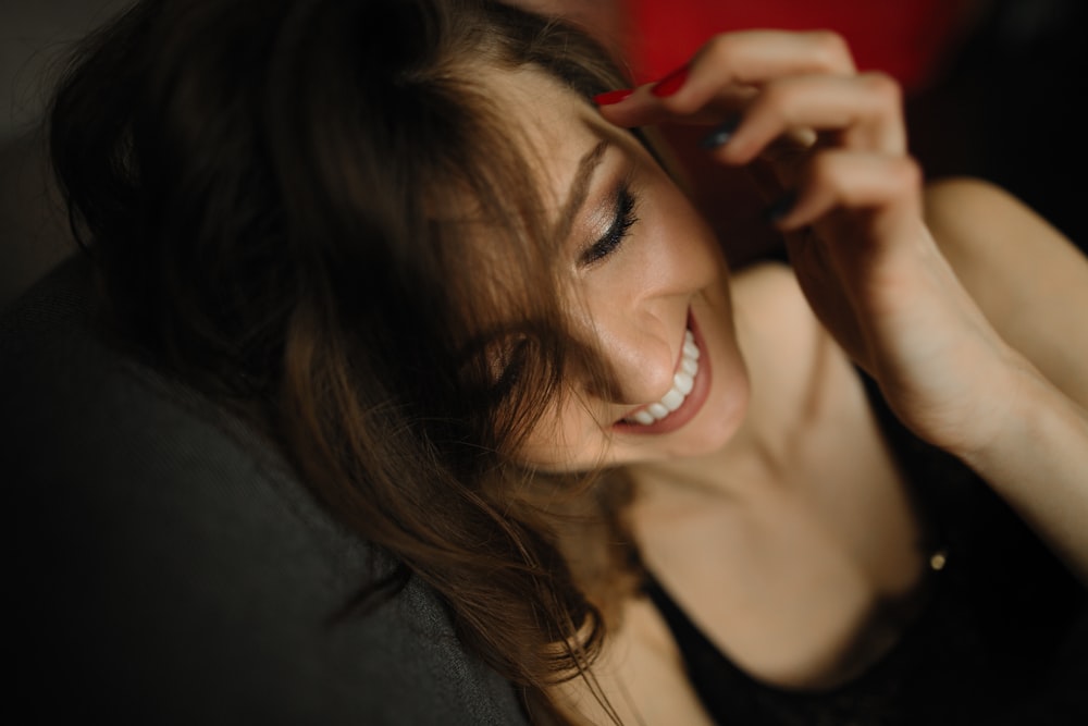 woman sitting smiling and holding her hair