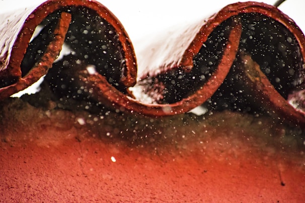 Close-up of freshly installed red clay tile roofing glistening under morning sunlight.