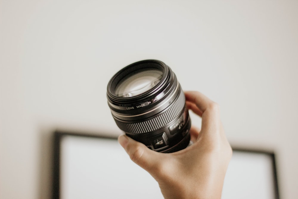 person holding DSLR camera lens