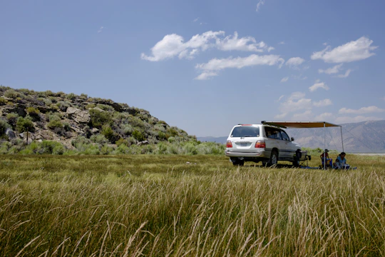 A roomy SUV parked by a lakeside with a family unloading picnic supplies.