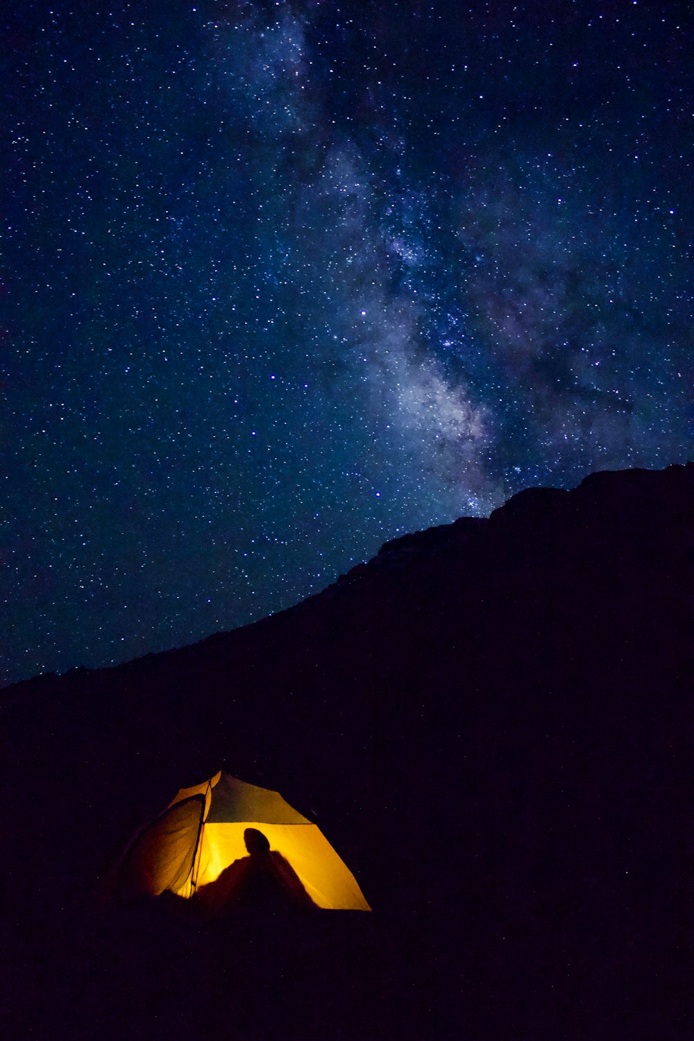夜間の山岳地帯の黄色いライトアップされたキャンプ