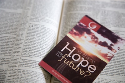 A pamphlet titled 'Is there Hope for the Future?' placed on an open page of the Bible. The pamphlet features a sky with clouds and the apparent colors of a sunrise or sunset.