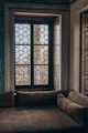 Comfortable seating area with a small sofa and decorative cushions near a window.