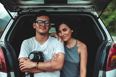 A young couple happily signing paperwork for their first car purchase at a modern dealership.