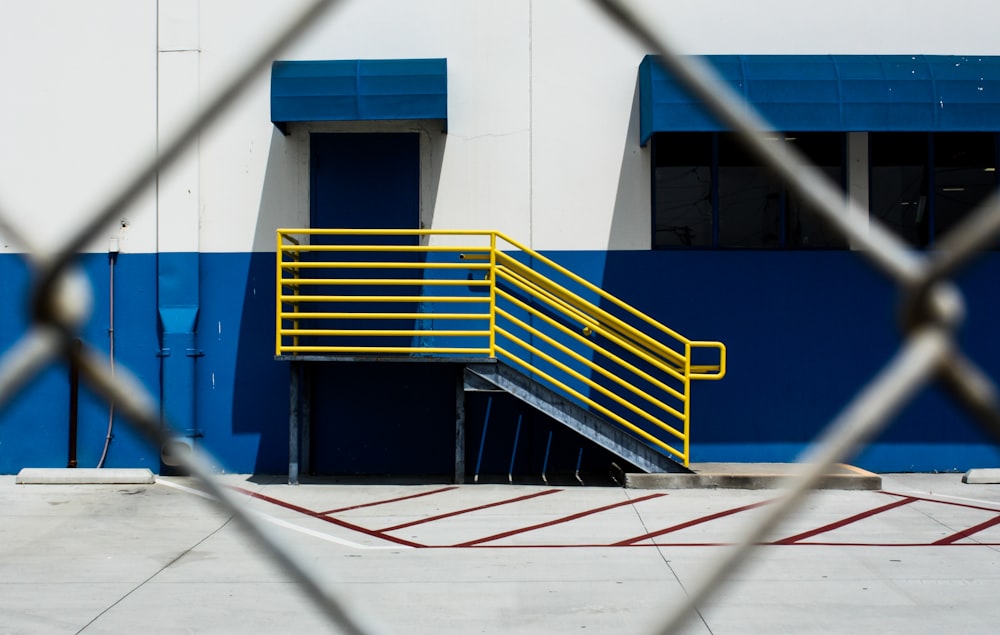 yellow handrails with stair beside white and blue wall