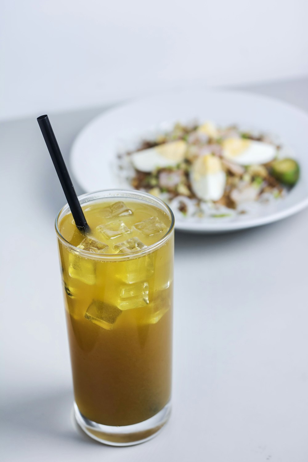 clear glass cup filled with yellow liquid and ice cubes