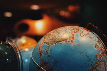 Close-up of a globe with golden accents highlighting popular international destinations under soft lighting.