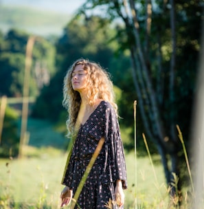 woman in black long-sleeved dress standing on grass field