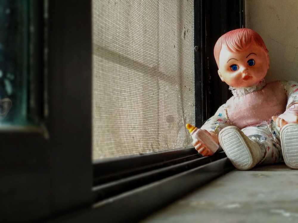 poupée de bébé assise sur la fenêtre