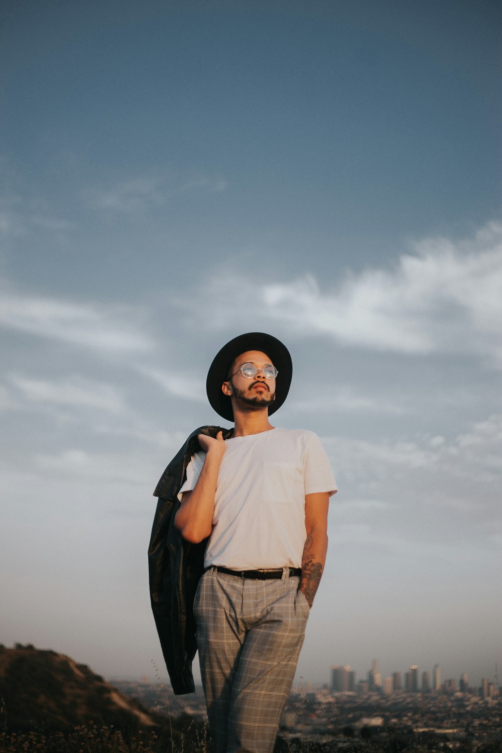 man on mountain behind cityscape