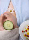 woman wearing blue robe lying with cucumber on eye
