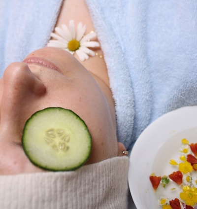 woman wearing blue robe lying with cucumber on eye