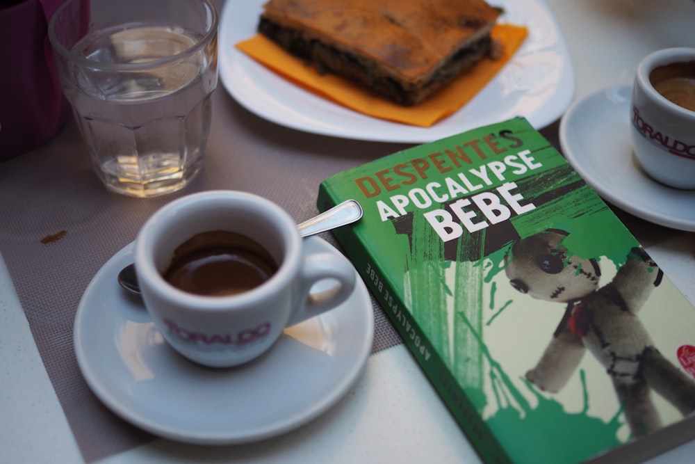 white ceramic teacup beside book