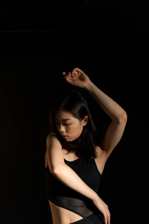 A graceful contemporary dancer stretching elegantly against a soft, glowing backdrop.