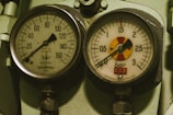 Two analog pressure gauges mounted on a metal surface, each displaying pressure measurements in bars. The left gauge has a range up to 160 bars, labeled with 'Bourdon' and 'Bain de Glycérine', while the right gauge goes up to 3 bars and includes a colored section on the dial.
