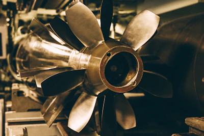 Close-up of a precision-engineered turbine blade gleaming under bright workshop lights.