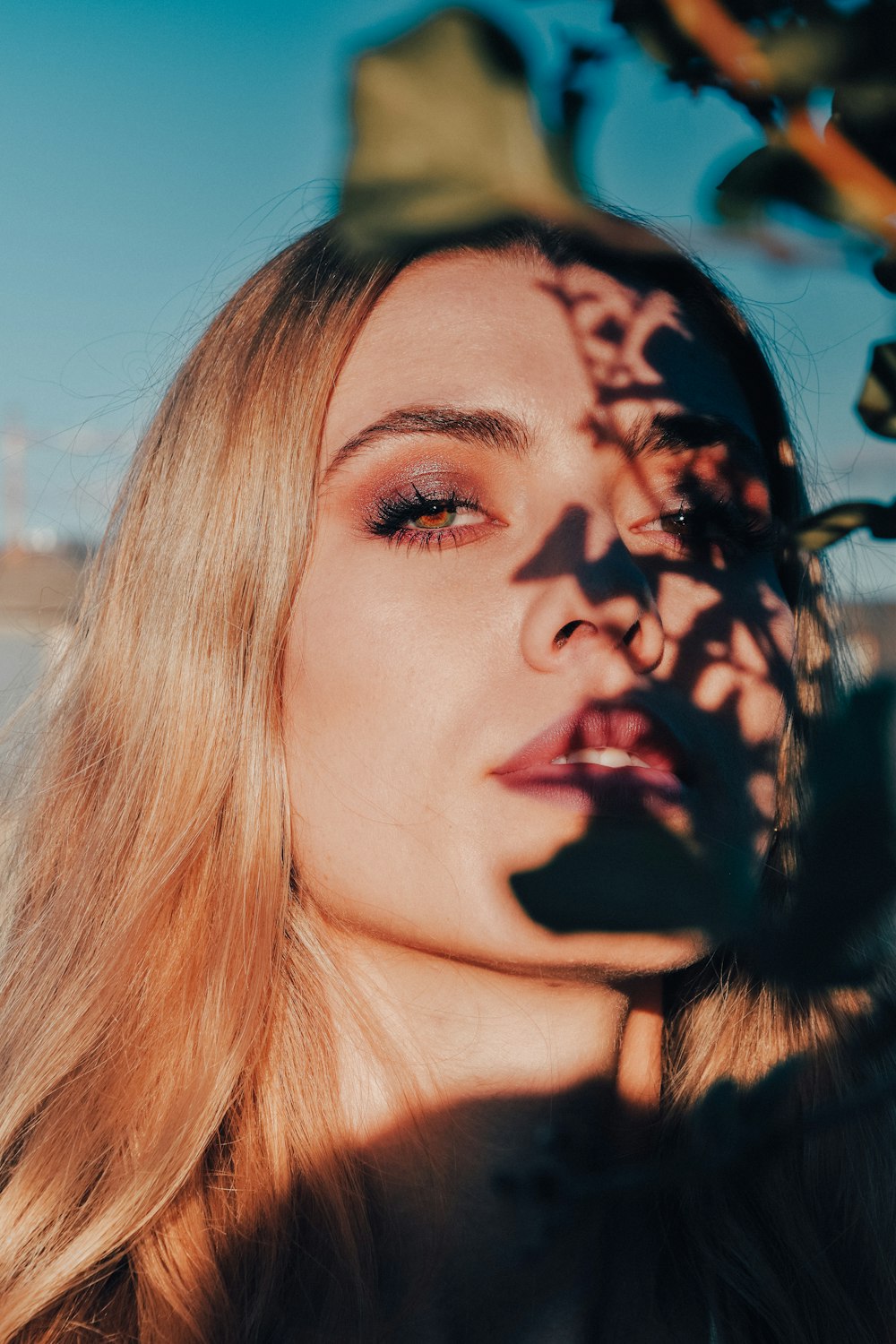 plant leaves shadow casted on woman's face during daytime