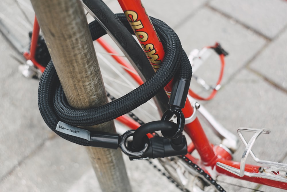 red and white bicycle locked in gray pole