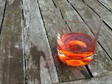 A vibrant glass of golden seabuckthorn juice catching sunlight on a rustic wooden table.