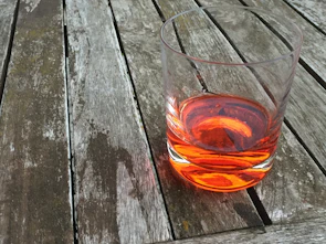 A vibrant glass of golden seabuckthorn juice catching sunlight on a rustic wooden table.